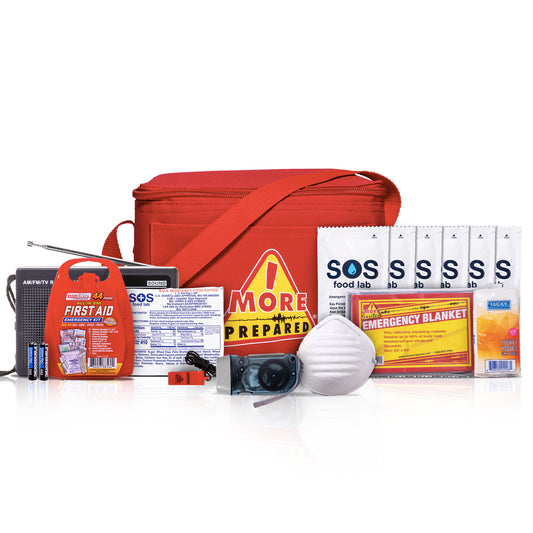 A comprehensive emergency preparedness kit arranged on a white reflective surface. The kit includes a red zippered carrying bag, a red first aid kit, a portable radio, a white dust mask, SOS food lab food and water packets, an emergency blanket, and other safety and first aid items.