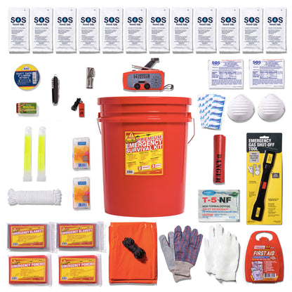 A comprehensive emergency survival kit laid out in a grid pattern around a large red plastic bucket. The kit contains various survival, first aid, and safety items including food bars, water pouches, a red emergency radio, a T-5 packet, face mask, white gloves, work gloves, emergency blankets, and other survival gear on a clean white background.